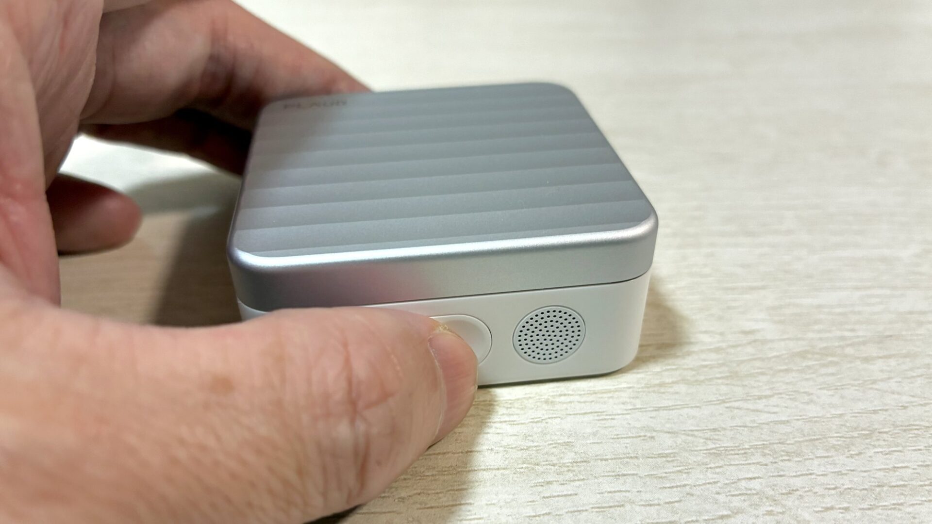 充電ケース正面の録音ボタンを指で長押しする様子